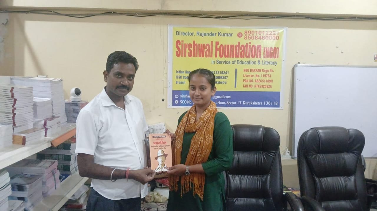 Director Rajender Kumar presenting a book to a student at the Foundation office